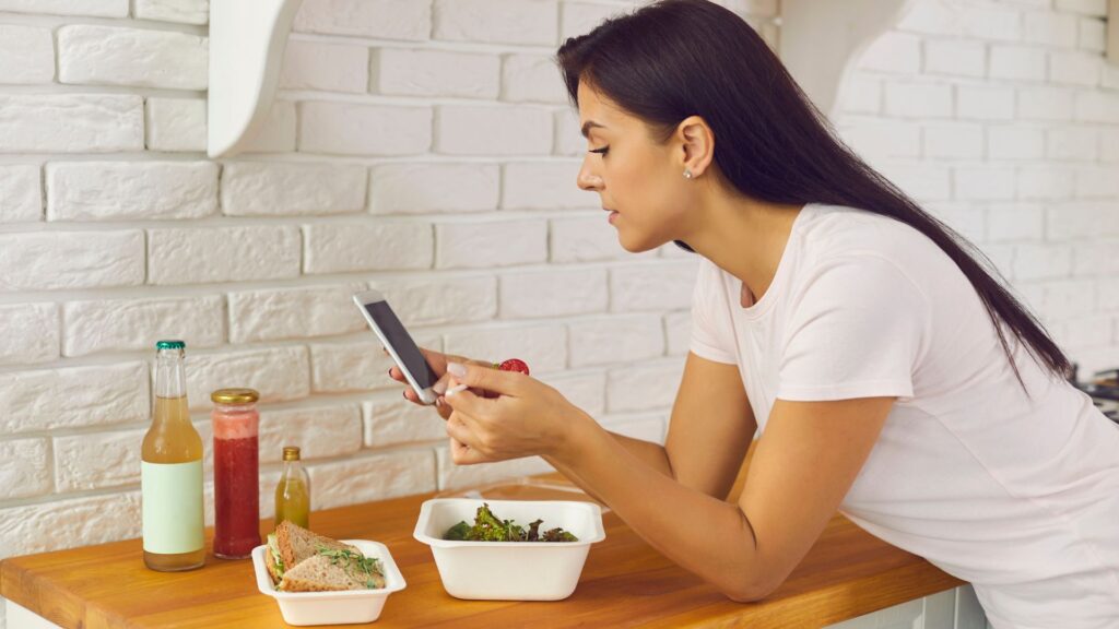 woman on her phone while eating healthy food
