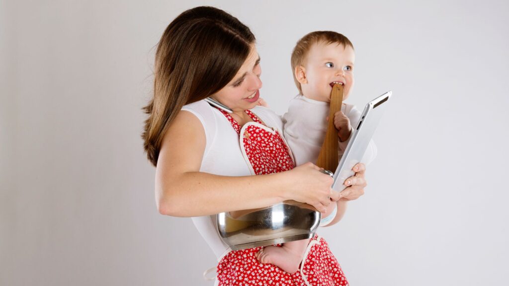 mom holding baby and cooking